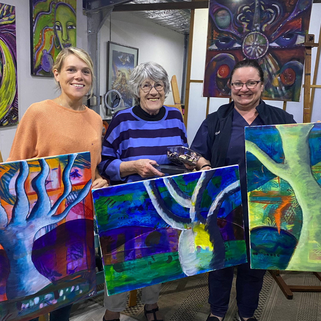 Different aged women smiling with their paintings